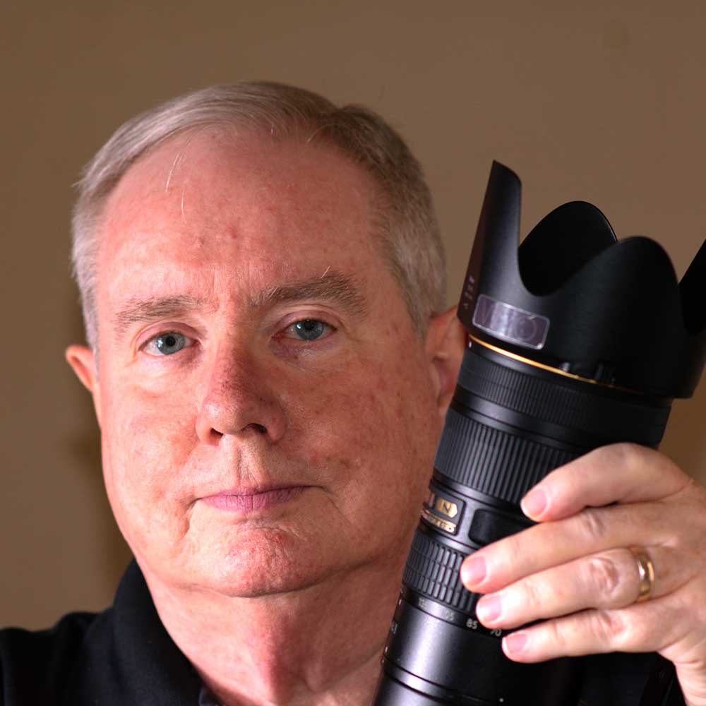 Greg Woods holding a large camara lens