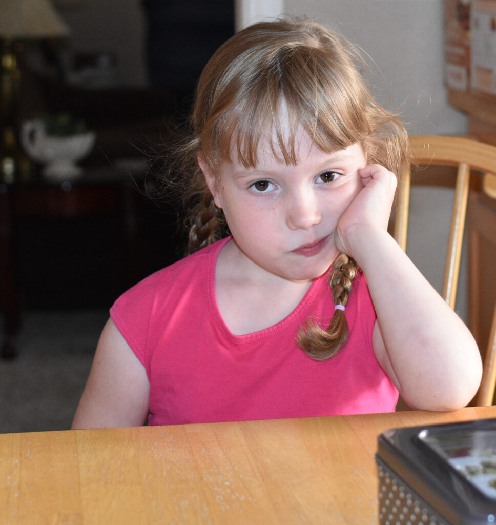 Seven year-old blond girl in pink blouse looking very serious